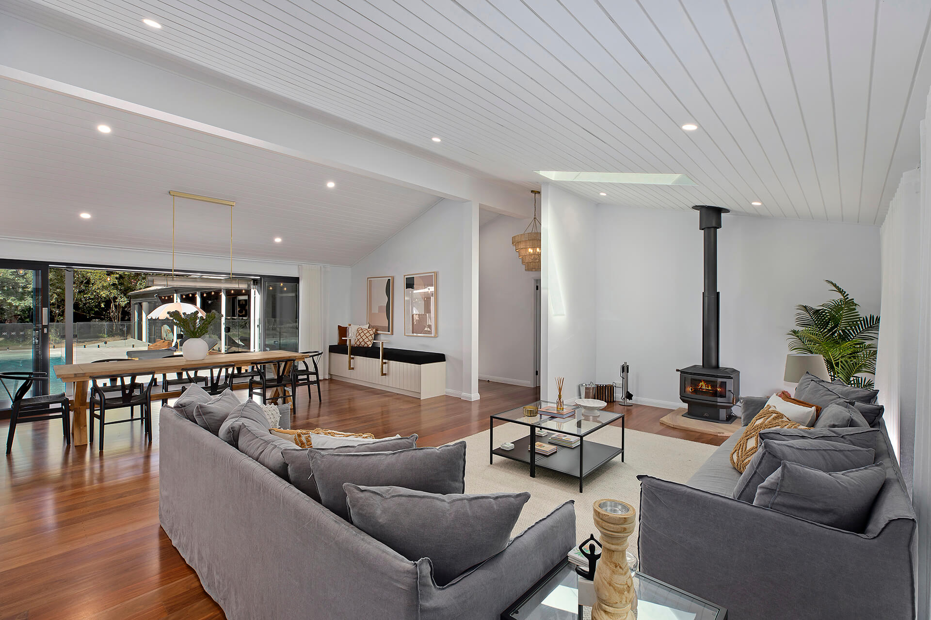 Living space with couch, dining table, fireplace with views of pool area in the background