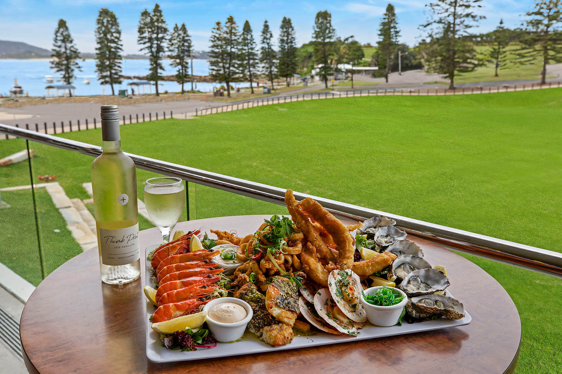 Assortment of seafood and alcohol with large open field and ocean in the background